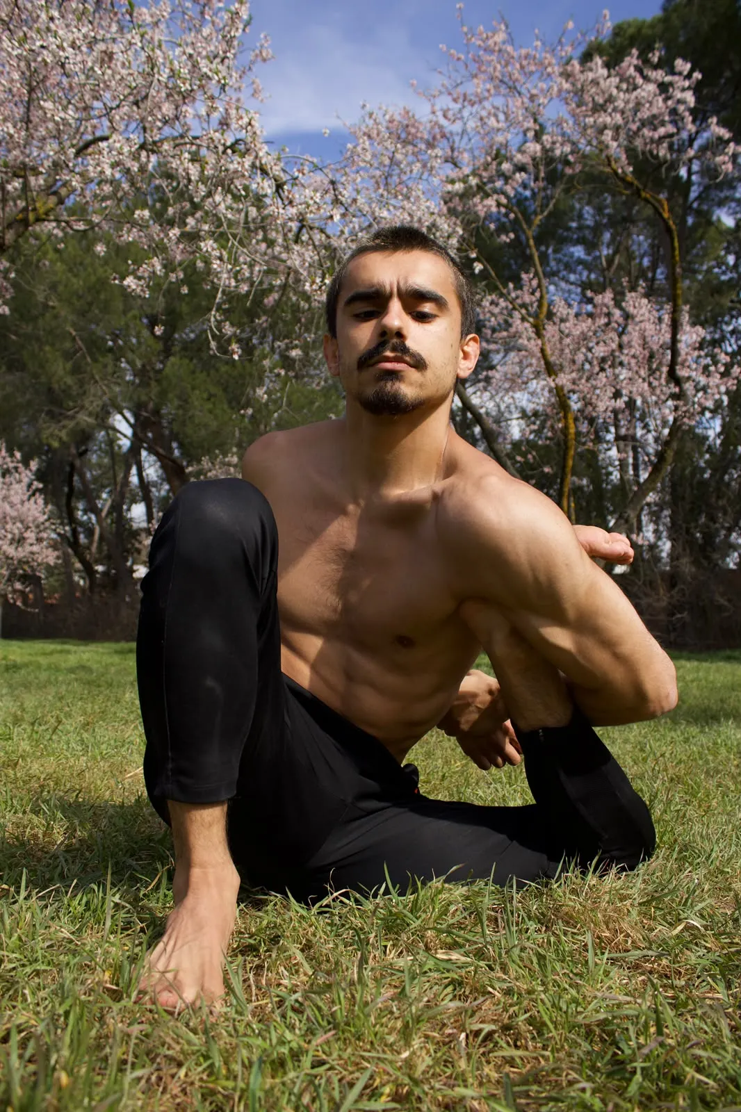Luis en torsión sentada entre almendros en flor