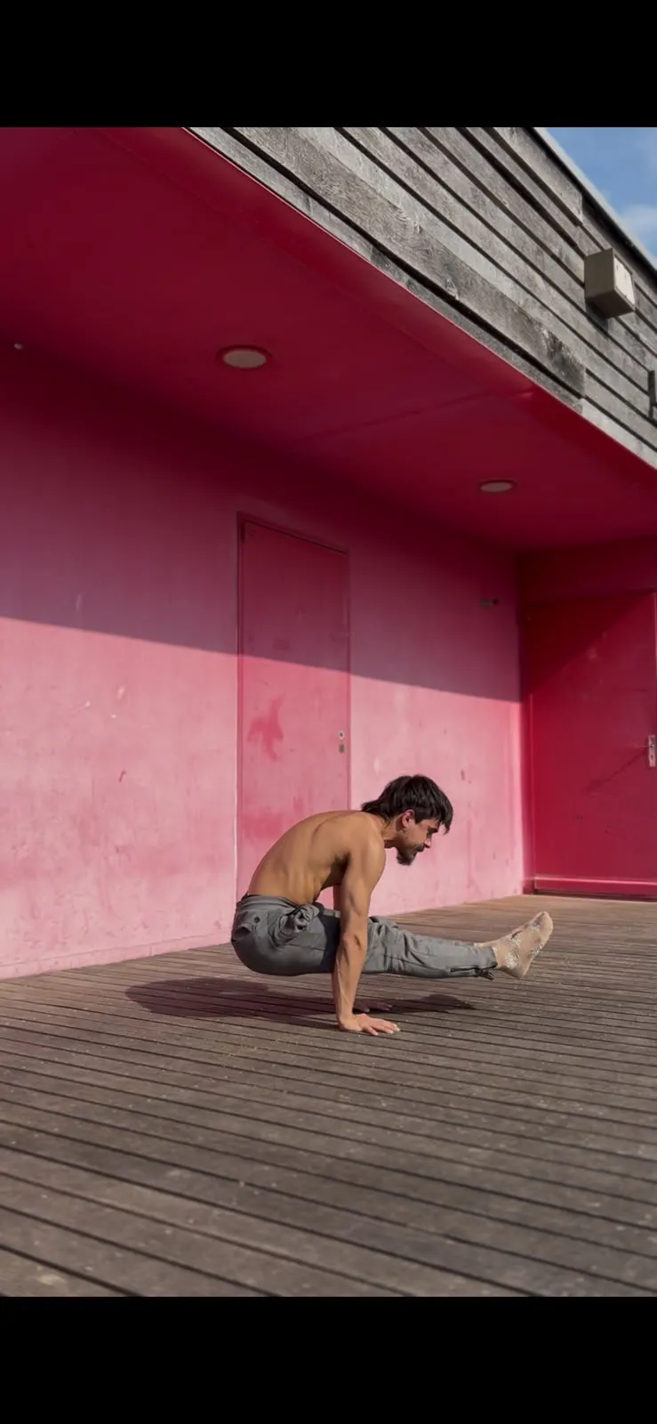 Practicante sosteniendo un press con las piernas extendidas frente a una pared rosa