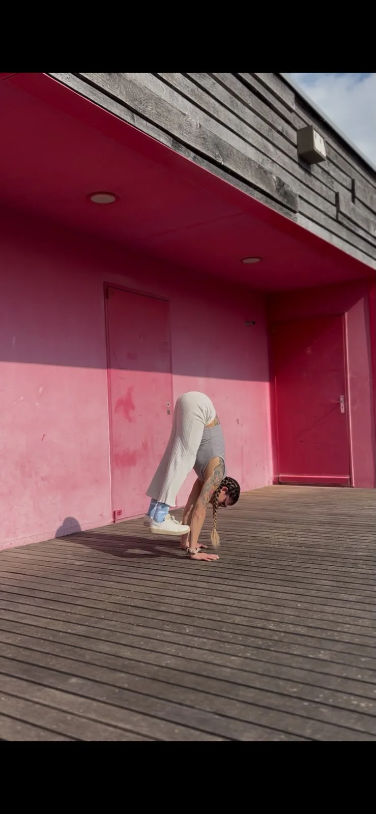 Practicante en parada de manos contra una pared rosa